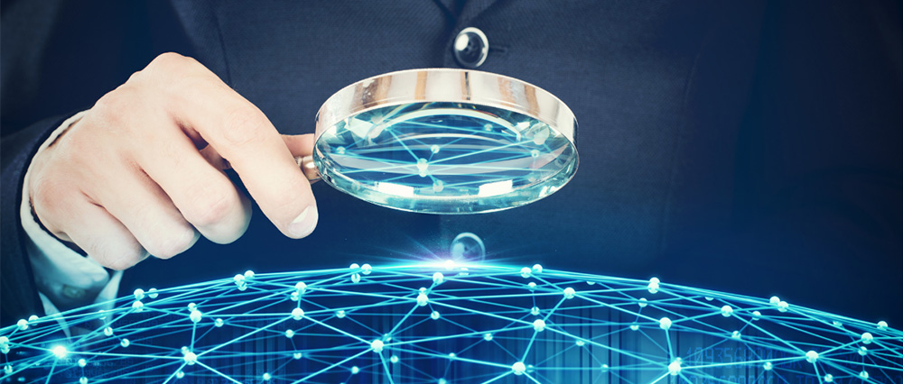 A person holding a magnifying glass over a digital globe